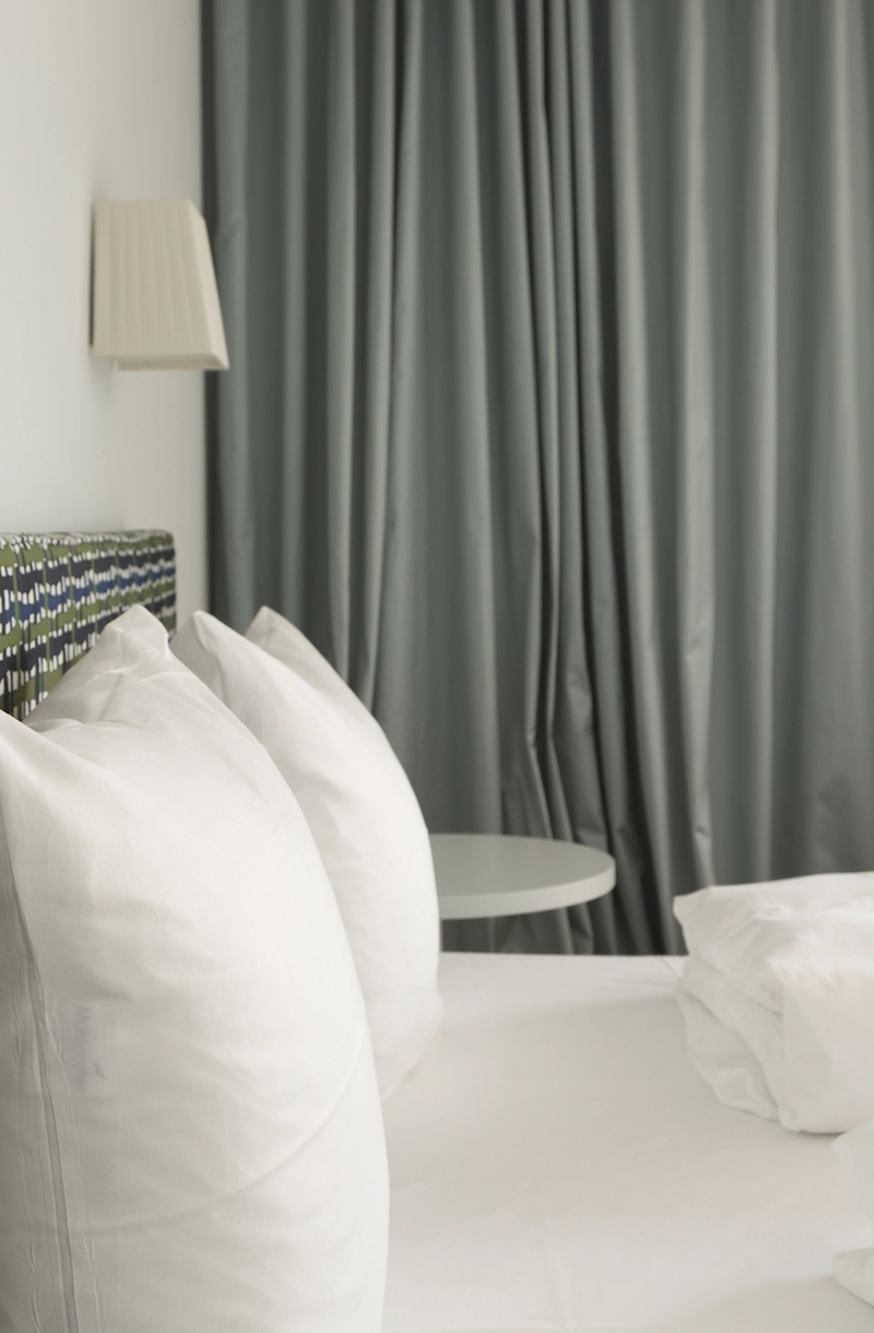 Detailansicht eines gemütlichen Doppelbetts mit zwei weißen Kissen im Hotelzimmer.