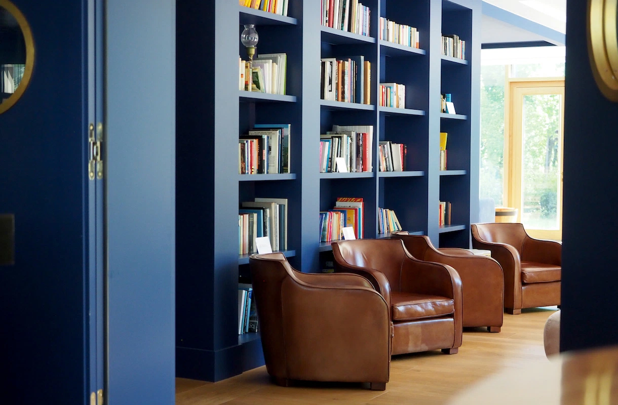 Leseecke mit braunen Ledersesseln und blauen Bücherregalen im Jugend- und Familienhotel Augustin.