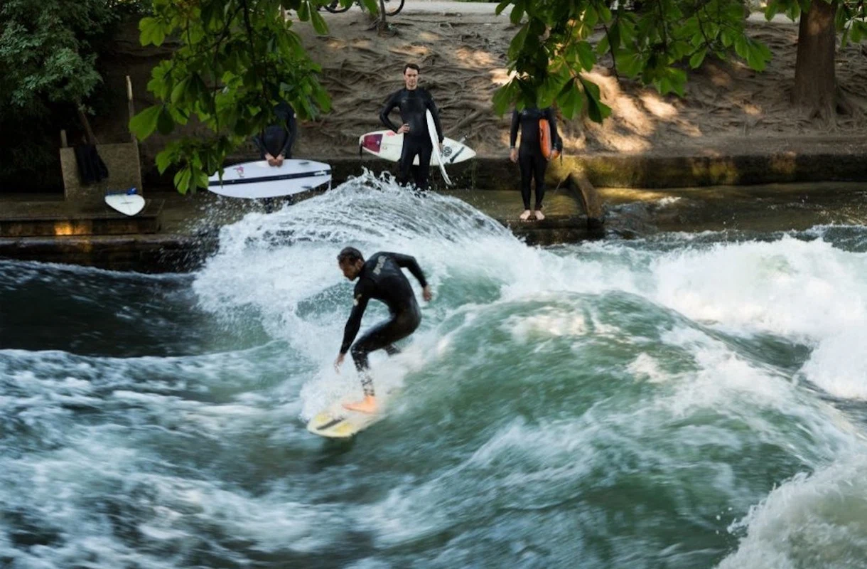Surfer reitet die berühmte Eisbachwelle im Englischen Garten in München