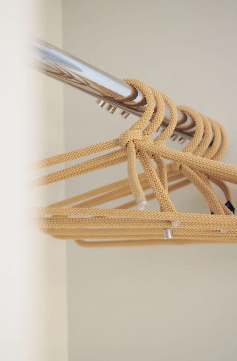 Kleiderbügeln aus geflochtenem Seilmaterial an einer Metallstange im Zimmer des Hotel Augustins