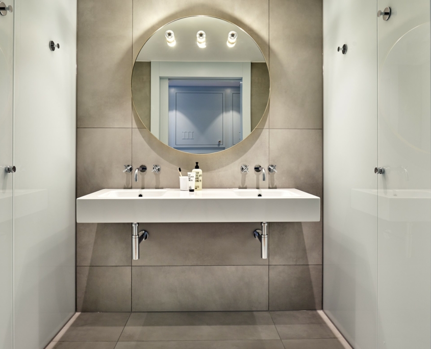 modernes Badezimmer mit großen runden Spiegel, Doppelwaschbecken und stilvollem Design