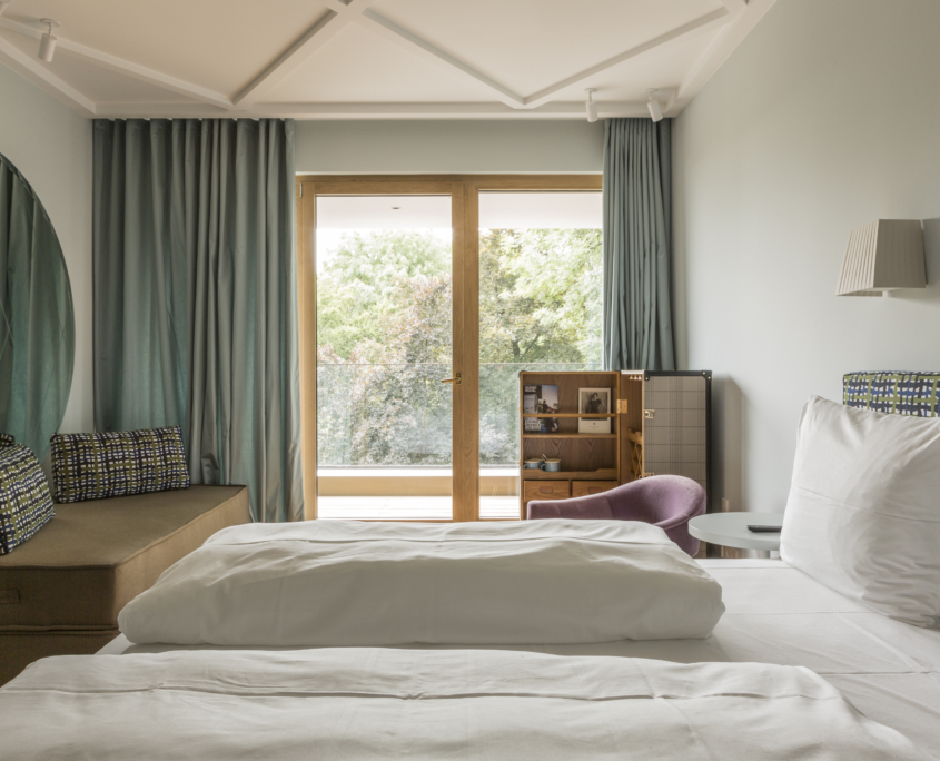 modernes Doppelzimmer im Hotel Augustin München mit großen Fenstern, Balkonzugang und stilvoller Einrichtung