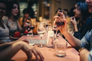 Menschen sitzen an einem Tisch und trinken Wein